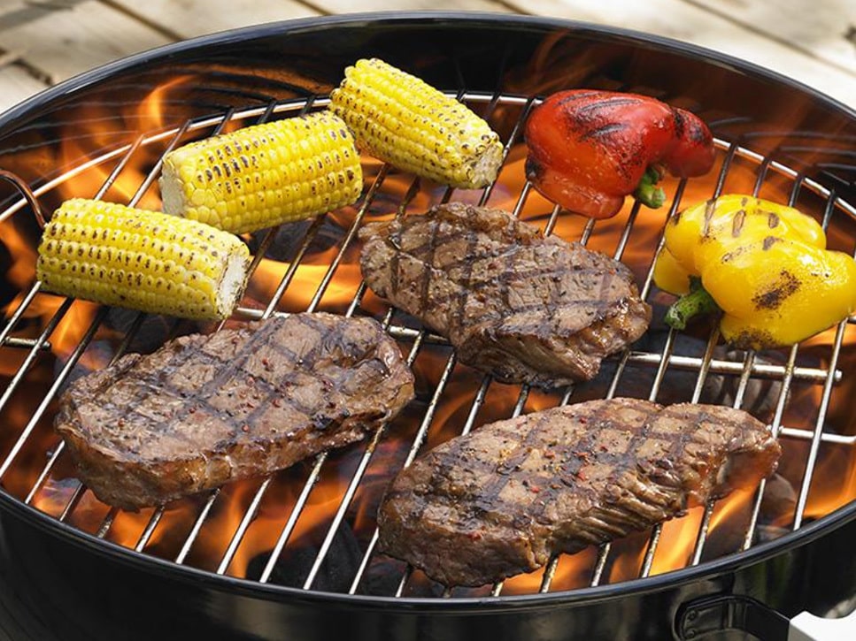 a pan filled with meat and vegetables cooking on a grill